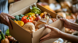Hands passing a Thanksgiving meal box filled with fresh produce and canned goods at a community food drive in natural light In a heartfelt act of giving, hands are shown passing a Thanksgiving meal box overflowing with fresh vegetables, bread, and canned goods