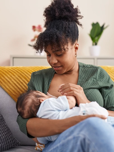 Mother and son sitting on sofa breastfeeding at home